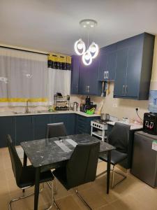 une cuisine avec des armoires bleues, une table et des chaises dans l'établissement G&G Homes Executive Suite, à Nakuru