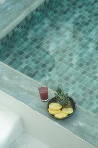a plate of pineapple and a drink next to a swimming pool at Casablanca Hotel - Centro Histórico in Santa Marta
