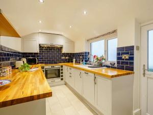 eine Küche mit weißen Schränken und blauen Fliesen in der Unterkunft 4 Bed in Broughton - in - Furness 90412 in Duddon