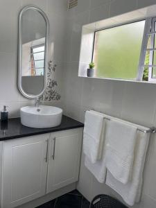 a bathroom with a sink and a mirror and towels at Graceful Getaway in Grahamstown