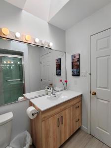 a bathroom with a sink and a toilet and a mirror at Bed Plus YVR in Richmond +27 photos