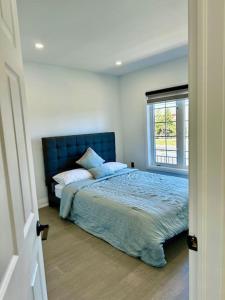 a bedroom with a bed with a blue headboard and a window at Private Luxury Full Home in Markham in Markham