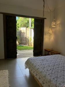 a bedroom with a bed and an open door at Kanau Surfe e Arte in Marechal Deodoro