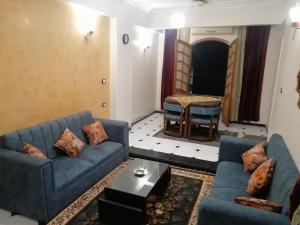 a living room with two blue couches and a table at Nile house in Jazīrat al ‘Awwāmīyah