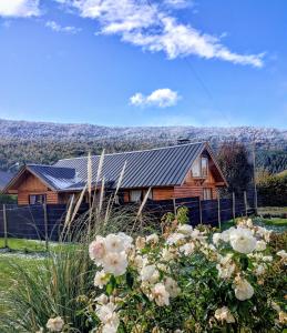 una casa de madera con techo solar y algunas flores en Cabaña los teros en San Martín de los Andes