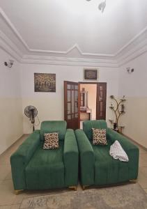 a living room with a green couch and a fan at MAISON MOUnADJA in Dakar