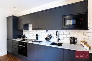 uma cozinha com armários pretos, um lavatório e um micro-ondas em 1 Bedroom Apartment - Central Richmond-upon-Thames em Richmond upon Thames
