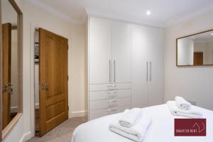 una camera da letto bianca con asciugamani bianchi su un letto di 1 Bedroom Apartment - Central Richmond-upon-Thames a Richmond upon Thames