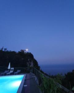 a pool with a view of the ocean at night at La Cicogna in Agerola