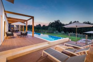 een terras met stoelen en parasols naast een zwembad bij Villa Istria Green in Kršan