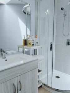 a white bathroom with a shower and a sink at Bed Plus YVR in Richmond