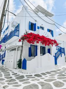a white building with blue windows and red flowers at Eleanna's Mykonos in Mýkonos City