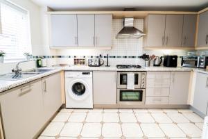 een keuken met witte kasten en een wasmachine en droger bij 3BR House with Parking near Iron Pier Thames River in Woolwich