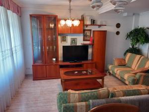 een woonkamer met een bank en een flatscreen-tv bij Chalet adosado a 100 mts playa in Laredo