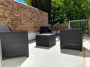 un gruppo di tre sedie di vimini e un muro di mattoni di Appartement T2, avec Terrasse. a La Roche-sur-Yon