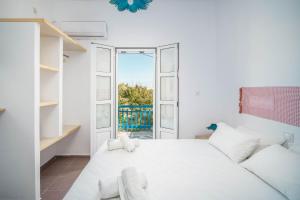 um quarto branco com uma cama grande e uma janela em Alcyone em Serifos Chora