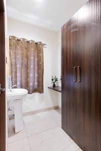 ein Badezimmer mit einer Holztür und einem Waschbecken in der Unterkunft VEERA RESIDENCY in Tiruvallūr