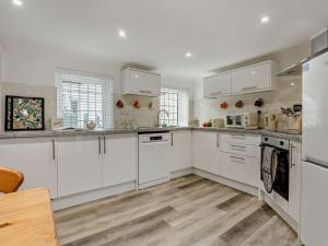 a white kitchen with white cabinets and wooden floors at 3 Bed in Bognor Regis 93447 in Bognor Regis