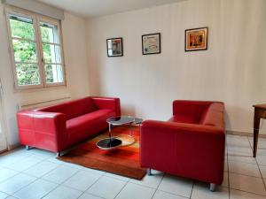 a living room with two red couches and a table at La curieuse petite maison in Vendôme