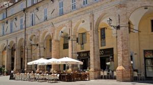 a building with tables and umbrellas in front of it at La Residenza del Cavallino in Fermo