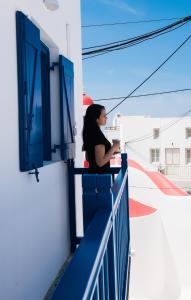 una donna in piedi su un balcone che guarda fuori da una finestra di Eleanna's Mykonos a Mykonos Città