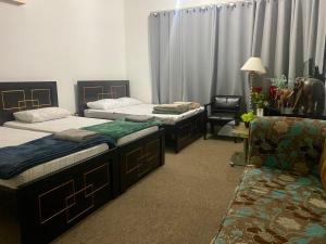 - une chambre avec deux lits, une chaise et un canapé dans l'établissement A Home Away From Home, à Abu Dhabi