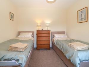 GaerwenにあるTy Mawrのベッドルーム1室(ツインベッド2台、ドレッサー付)