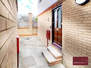 a brick building with a door and a sidewalk at Hitchin - St Anne's - 2 bed coach house & Parking in London Colney