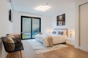 een witte slaapkamer met een groot bed en een raam bij Villa Luxe by Atlantic Holiday in Ribeira Brava +36 foto's