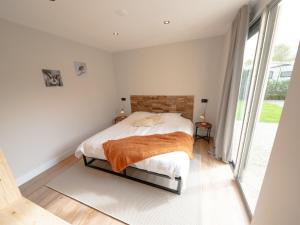 a bedroom with a bed and a large window at Wellness Bungalow with whirlpool and sauna in Zevenhuizen