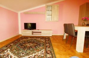 een woonkamer met een tv en een tafel en een tapijt bij Casa Vacanze Sabrina in Polpenazze del Garda