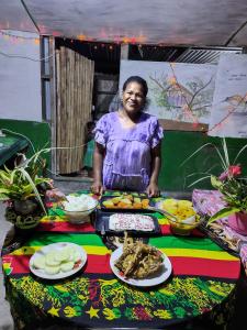 una mujer parada frente a una mesa con comida en Tanna tree house and bangalows en Lénakel