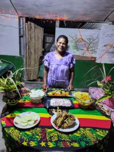a woman standing in front of a table with food at Tanna tree house and bangalows in Lénakel