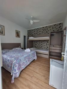 1 dormitorio con 2 camas y ventilador de techo en Pousada Aconchego na Praia, en Praia Grande