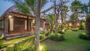 ein Haus mit einem Garten mit Palmen und Lichtern in der Unterkunft Picturesque Private Joglo Villa Near Monkey Forest in Ubud