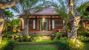ein Haus mit Palmen davor in der Unterkunft Picturesque Private Joglo Villa Near Monkey Forest in Ubud
