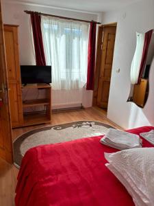 a bedroom with a red bed with a red blanket at Pensiunea Luminita in Bran