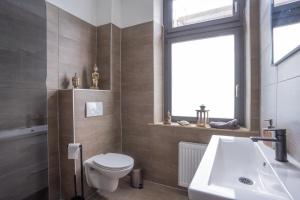 baño con aseo y lavabo y ventana en Duisburger Hostel, en Duisburg