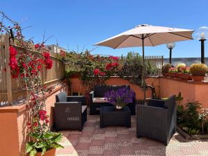 eine Terrasse mit Stühlen, einem Sonnenschirm und Blumen in der Unterkunft Anthea B&B in Ercolano