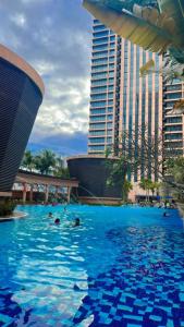 people swimming in a large swimming pool with buildings at The Hotel and Apartment At Times Square in Kuala Lumpur