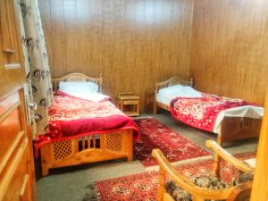 Habitación pequeña con 2 camas y silla en Serene Guest House en Gilgit