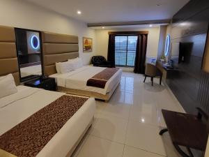 a hotel room with two beds and a desk at Grand Millennium Hotel in Lahore