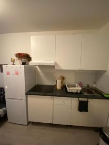 eine Küche mit weißen Schränken und einem weißen Kühlschrank in der Unterkunft Apparemment meublé et cosy in Gennevilliers