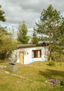 a small white building in a field with trees at Gospodarstwo Agroturystyczne Kłączno in Kłaczno