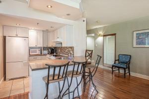 a kitchen with a table and chairs and a refrigerator at Le Bordeau à Saint-Sauveur in Saint-Sauveur-des-Monts