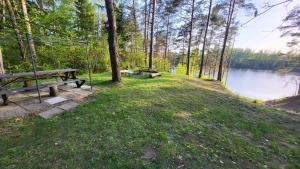 two picnic tables in the grass next to a lake at EKO Domek u Siemion in Raczki