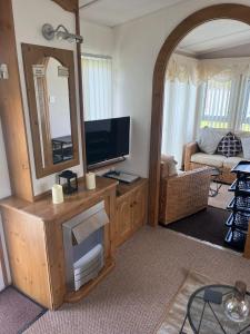 a living room with a television and a mirror at A7 caravan The Chase Ingoldmells in Ingoldmells