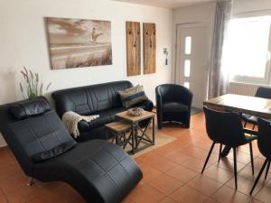 una sala de estar con un sofá de cuero negro y sillas en Strandperle 2 - a78241, en Loissin