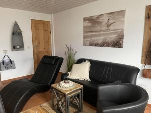 una sala de estar con un sofá de cuero negro y sillas en Strandperle 2 - a78241, en Loissin