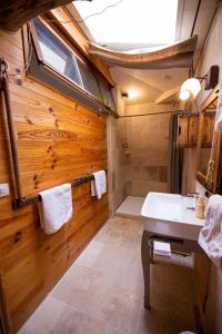 uma casa de banho com paredes de madeira, um lavatório e um chuveiro em Domaine De Chantemerle B'nB em Marsac